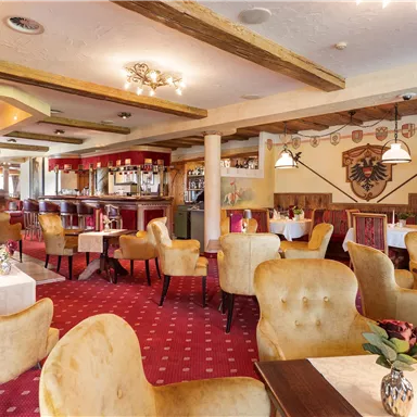 Ein elegantes Restaurant mit bequemen, samtigen Stühlen und warmem Licht. Die Wände sind mit traditionellen Dekorationen geschmückt und der Boden ist mit rotem Teppich bedeckt.