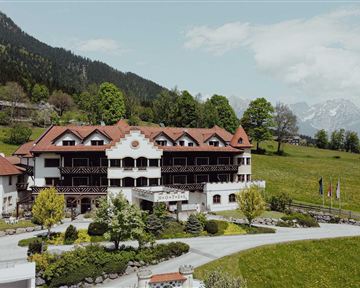 A charming hotel nestled in a picturesque mountain landscape. Surrounded by green meadows and trees, it exudes an inviting atmosphere.