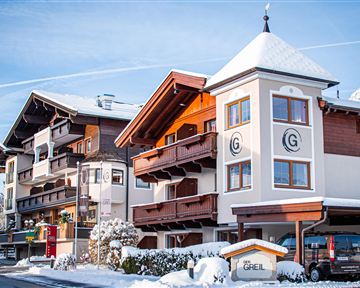 An attractive hotel building in the snow, surrounded by a picturesque winter landscape. Clear blue skies and snow-covered roofs create a serene atmosphere.