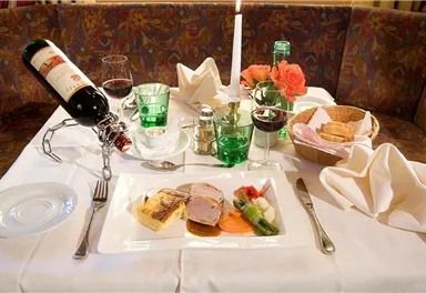 An elegantly laid table with a delicious dish, red wine, and a candle. The ambiance is cozy and inviting.