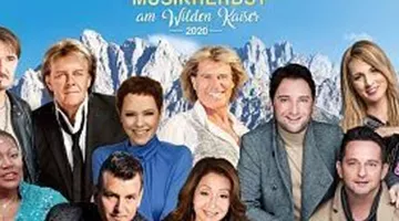 A group of artists poses in front of a stunning mountain landscape. The event "Music Autumn at Wilden Kaiser 2020" is announced.