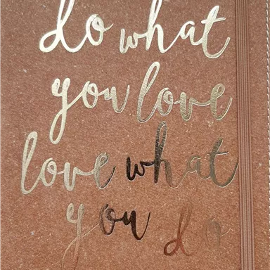 A notebook with the motif "Do what you love, love what you do" in golden letters. The background is brown and highlights the text.