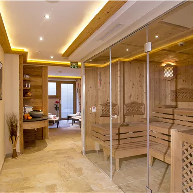A modern sauna area made of wood with soft lighting. The space is designed in a minimalist and inviting way, featuring large glass walls and a cozy atmosphere.