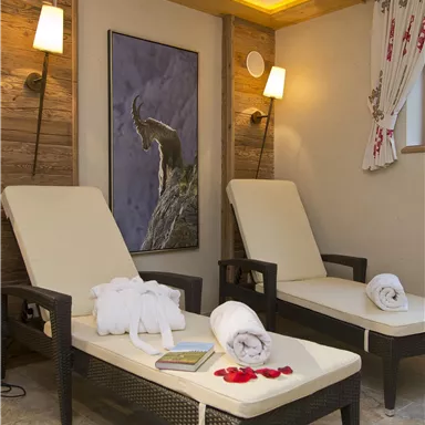 A cozy wellness area with two rattan lounge chairs. Soft lighting and a piece of art on the wall create a relaxing atmosphere.