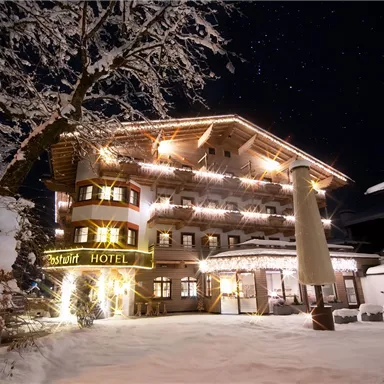 A picturesque hotel in the snow, beautifully illuminated under the starry sky. The winter landscape creates a cozy atmosphere.