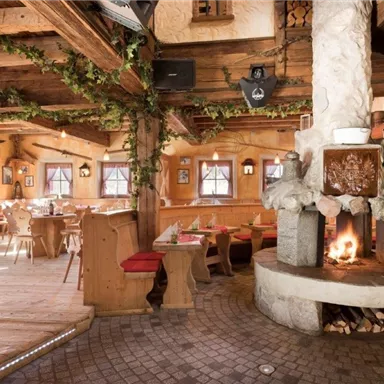 A cozy restaurant with wooden paneling and a rustic atmosphere. In the center stands an inviting fireplace that provides warmth.