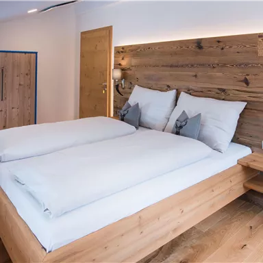 A modern bedroom with a double bed and light wood details. The cozy atmosphere is highlighted by the warm wall colors and soft lighting.