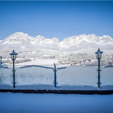 Eine verschneite Landschaft mit majestätischen Bergen im Hintergrund. Der klare blaue Himmel sorgt für eine idyllische Winteratmosphäre.