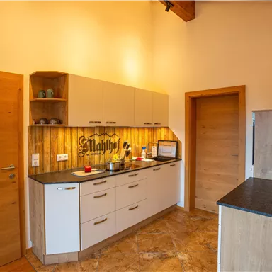 Eine moderne Küche mit hellen Möbeln und Holzdetails. Der Raum ist gut beleuchtet und freundlich gestaltet.