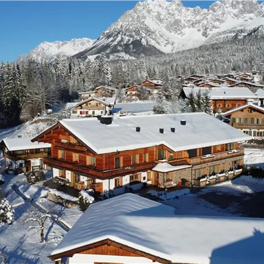 A picturesque Alpine landscape with snow-capped mountains. In the foreground, there are charming wooden houses in a tranquil, wintry setting.