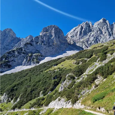 An impressive mountain landscape with steep rocks and green grass. The clear sky highlights the beauty of nature.