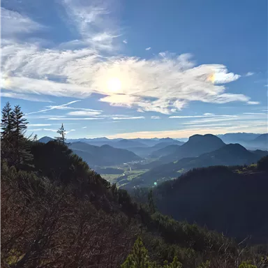 A beautiful mountain landscape with a clear sky and gentle hills. The sun shines over the valley and the surrounding mountains.
