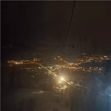 A nighttime view from a cable car of a illuminated city. The lights sparkle in the darkness, creating an atmospheric ambiance.