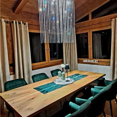 A modern dining area with a large wooden table and stylish chairs. A striking light fixture hangs over the table.