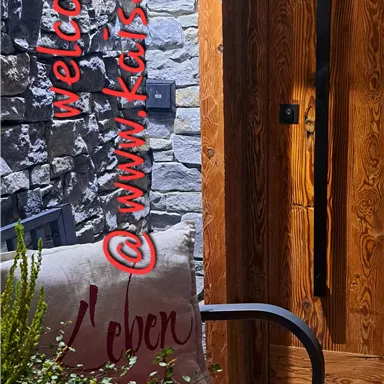 An inviting entrance with wooden cladding and a cozy bench. On the bench lies a cushion with the inscription "Life."