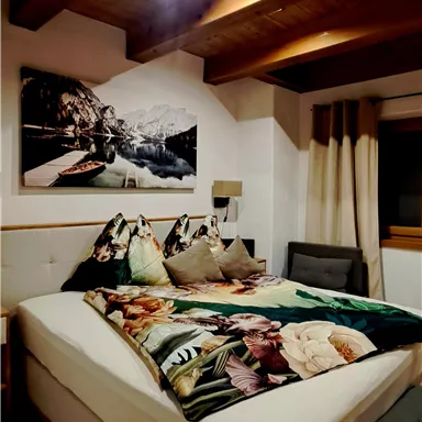 A cozy bedroom with a large bed and wooden ceilings.
A decorative picture hangs on the wall, and the decor is modern and inviting.