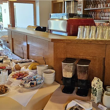 A rich breakfast buffet with various dishes and drinks. In the background, an inviting bar area can be seen.