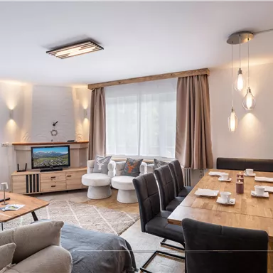 A modern living room with a large dining table and comfortable seating. 

Large windows let in plenty of light and create a cozy atmosphere.