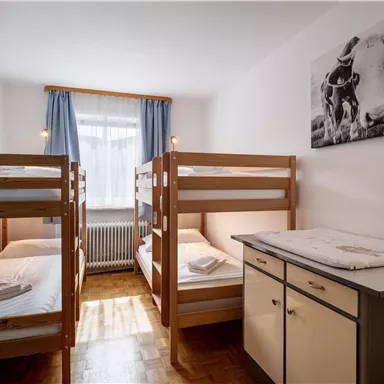 A simple bedroom with two bunk beds and a wardrobe. On the wall hangs a picture of cows.