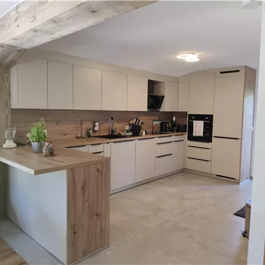 A modern kitchen with bright furniture and an open design. The room is well-lit and feels inviting.