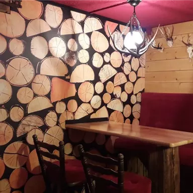 A cozy gastro operation with rustic wooden optics. The walls are decorated with wooden slices, and the seating areas invite you to linger.