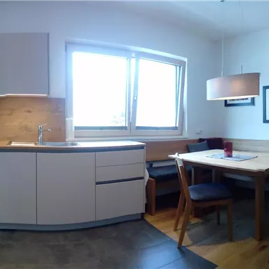 A modern kitchen with a cozy dining area. Bright colors and plenty of natural light create an inviting atmosphere.