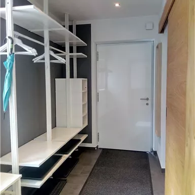 A bright hallway with modern storage options and a white door. The walls are in neutral colors, creating an inviting atmosphere.