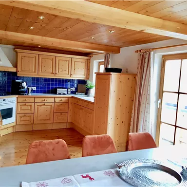 Eine helle Küche mit Holzmöbeln und blauen Fliesen. Der Essbereich ist mit einem Tisch und Stühlen ausgestattet.