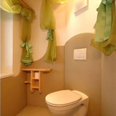 Eine moderne Toilette mit einem minimalistischen Design. Die Wände sind in neutralen Tönen gehalten, und grüne Vorhänge verleihen dem Raum eine frische Note.
