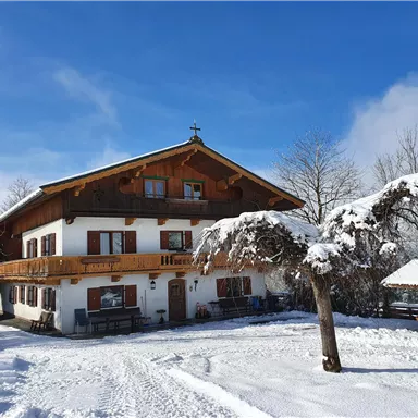 A traditional house in the snow with a beautiful balcony.
Surrounded by snow-covered trees and a clear blue sky.