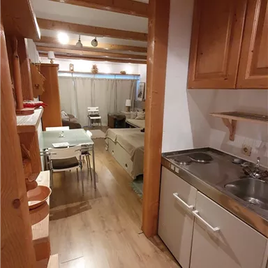 Eine gemütliche Küche mit Holzmöbeln und moderner Ausstattung. Der Blick zeigt einen Essbereich im Hintergrund.