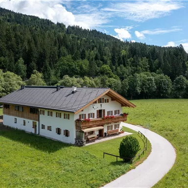 A beautiful house in a rural setting, surrounded by green meadows and forests. The sky is clear and the landscape radiates tranquility.