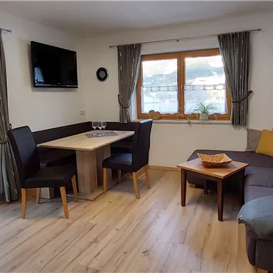 A cozy living area with a sofa, a table, and chairs. Large windows provide a view of the snowy landscape.