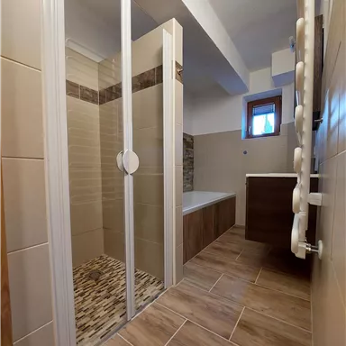 Ein modernes Badezimmer mit Dusche und Badewanne. Es hat eine helle Farbgestaltung und Fenster für natürliches Licht.