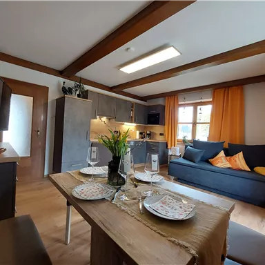 A cozy apartment with a modern dining area and a comfortable couch. Bright windows and appealing decoration create an inviting atmosphere.