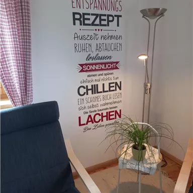 A cozy room with two armchairs, a floor lamp, and wall decor that offers relaxation tips. The atmosphere is inviting and calming.