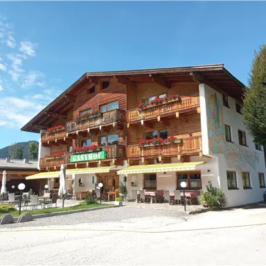 A charming inn with a wooden facade and balconies. The sky is clear, and the outdoor area is invitingly designed.