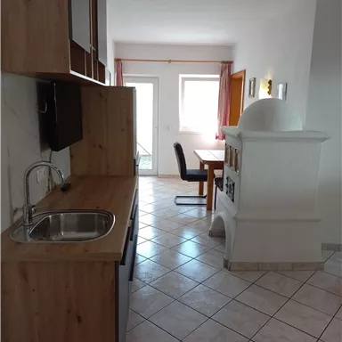 A modern kitchen with wooden cabinets and a small table. The space is bright and inviting.