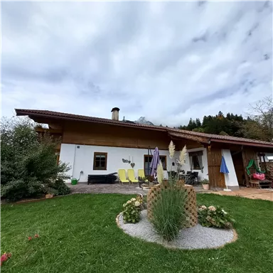 A charming house with a well-maintained garden and colorful flowers. The terrace is equipped with deck chairs and sun umbrellas.
