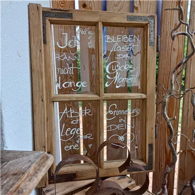 A creative wood window with handwritten texts that focus on memories and the enjoyment of the moment. It is rustic and gives the room a personal touch.