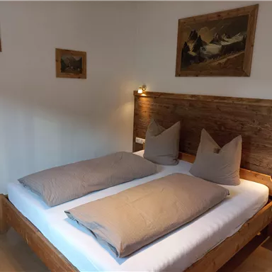 A cozy bedroom with a double bed and soft pillows. Some pictures hang on the walls, creating a warm atmosphere.