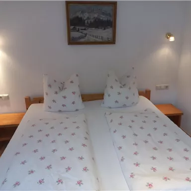 A cozy bedroom with two single beds and soft pillows. Gentle lighting creates an inviting atmosphere.