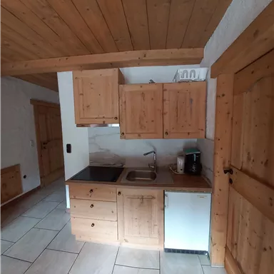 A cozy wooden kitchen with modern appliances. The room has bright tiles and an inviting atmosphere.