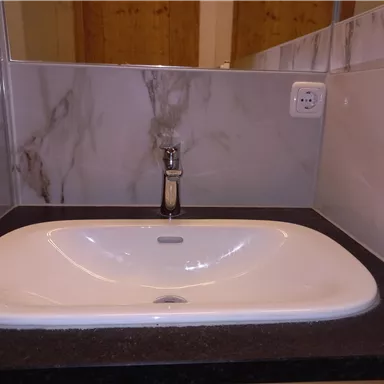 A modern sink on a dark countertop with elegant walls. The faucet is made of shiny metal.