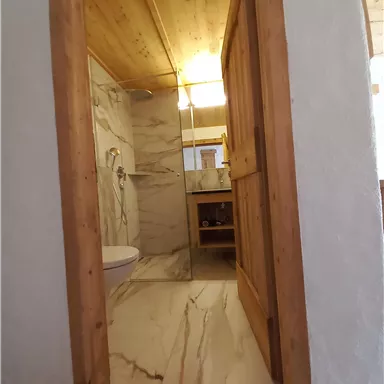A modern bathroom with marbled walls and a wooden frame. The light is warm and creates an inviting atmosphere.