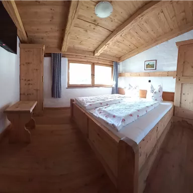 A cozy bedroom with wooden paneling and two beds. The windows let in plenty of daylight.