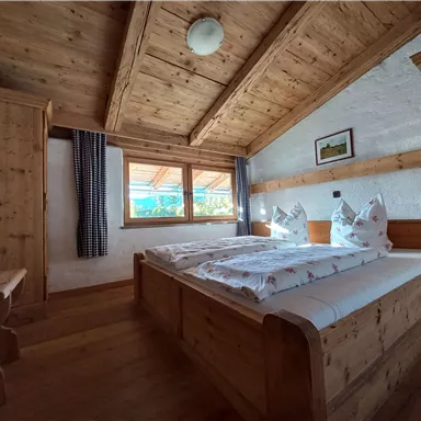 A cozy bedroom with wooden furniture and two beds. The windows offer a nice view outside.