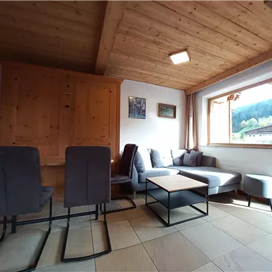 A cozy living space with a sofa area and a table. Large windows offer a view of the mountains.
