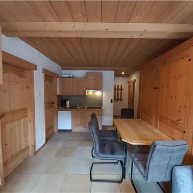 A cozy kitchen with a dining table and modern chairs. The walls are made of light wood, creating a warm atmosphere.