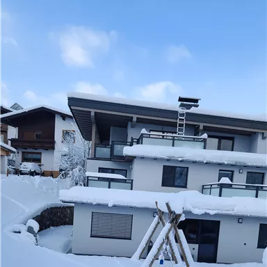 A modern building with several floors, surrounded by a thick layer of snow. The sky is clear and blue, creating a peaceful winter atmosphere.